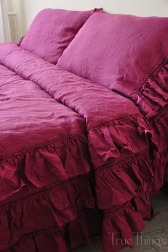 a bed with pink sheets and ruffles on it