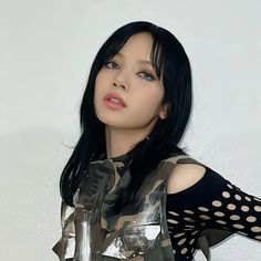 a woman with black hair wearing a silver shirt and polka dot gloves, posing for the camera