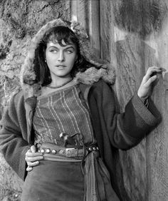 an old black and white photo of a woman leaning against a wall