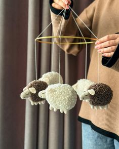 a woman is holding two sheep mobiles in her hands