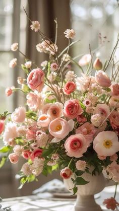 a vase filled with lots of pink flowers on top of a table next to a window