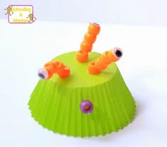 a green cupcake liner with orange plastic worms sticking out of it's top