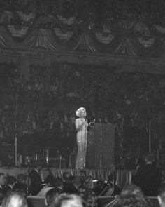 a woman standing on top of a stage in front of a crowd