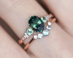 a woman's engagement ring with an oval green stone surrounded by small white diamonds