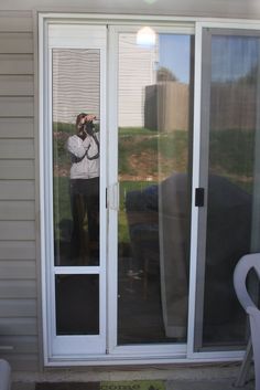 a man taking a photo through the glass door of a house with his camera in hand