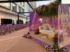 an outdoor ceremony setup with purple and white flowers on the aisle, couches and chairs