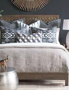 a bed with blue and white pillows on top of it next to a wooden headboard