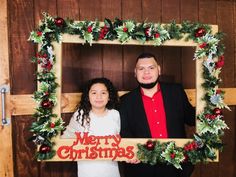 a man and woman standing next to each other in front of a christmas frame