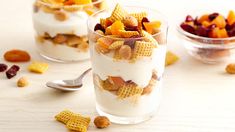 two glasses filled with cereal sitting on top of a table next to some crackers