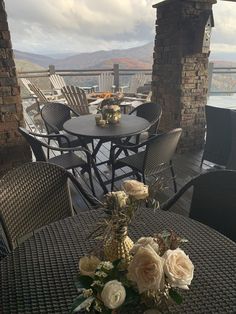 an outdoor table with flowers on it and chairs around it, overlooking the mountains in the distance