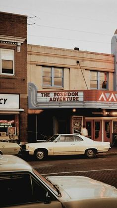 an old movie theater with cars parked in front