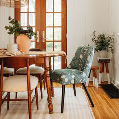 a dining room table with two chairs and a potted plant