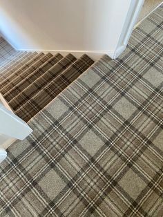 carpeted stairs leading up to a white door in a room with beige and black plaid carpet