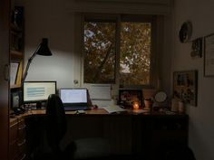 a desk with two computers on it in front of a window