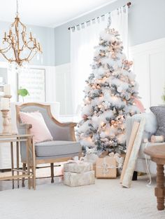 a decorated christmas tree in the corner of a living room with white and pink decorations