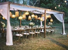 an outdoor wedding setup with white drapes and hanging lanterns