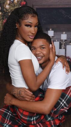 a man and woman hugging in front of a christmas tree