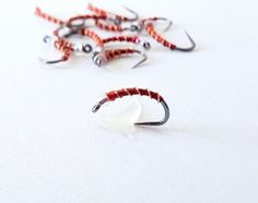 several different types of fishing lures on a white surface with red and black beads