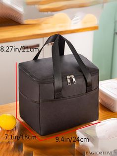 a large black bag sitting on top of a wooden table next to a bowl and container