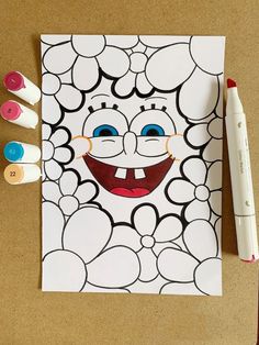 a coloring page with markers and crayons next to it on a brown surface