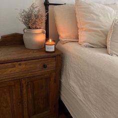 a bedroom with a bed, night stand and vase on the nightstand next to it