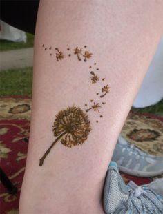 a small dandelion tattoo on the right side of the leg, with tiny flowers coming out of it