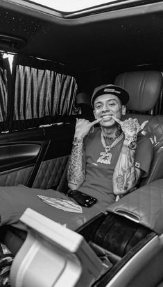 a man sitting in the back seat of a car with tattoos on his arm and chest