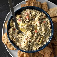 a bowl of dip with crackers on the side