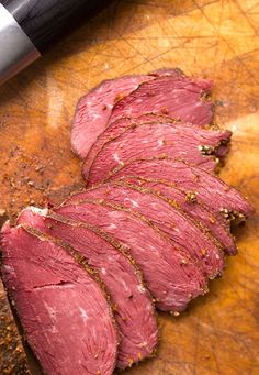 sliced meat sitting on top of a wooden cutting board