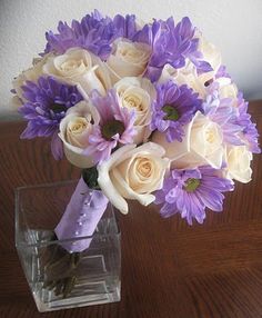 purple and white flowers in a vase on a table