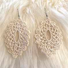 two crocheted earrings on top of a furry surface