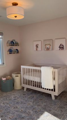 a baby's room with a crib, rug and pictures on the wall