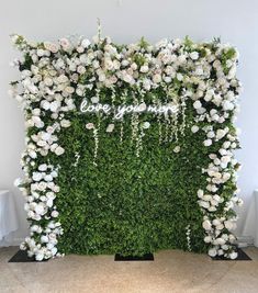 a white flower covered wall with the word love spelled in cursive writing