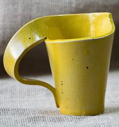 a yellow coffee cup sitting on top of a table next to a white cloth covered couch