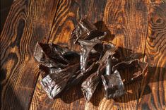 some pieces of dark chocolate on a wooden table with the peels still in it