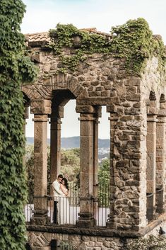 a bride and groom standing on the balcony of an old building with ivy growing around it