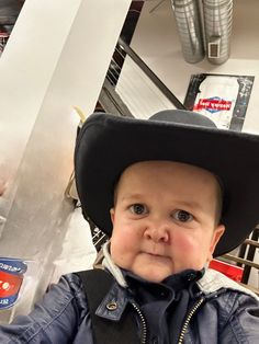 a little boy wearing a cowboy hat in a store