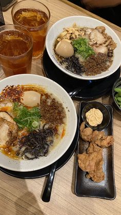 two plates of food sit on a table next to some drinks and other dishes with different foods in them