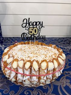 a birthday cake sitting on top of a blue tablecloth with a happy 50th sign