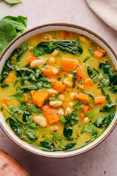 a bowl of soup with spinach, carrots and chickpeas