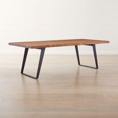 a wooden table sitting on top of a hard wood floor next to a white wall