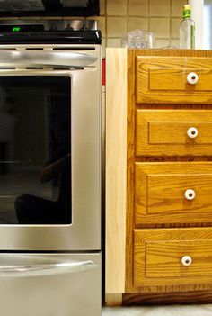 a silver oven sitting next to a wooden dresser