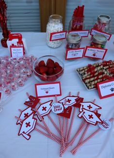 a table topped with lots of desserts and candies on top of a white table cloth