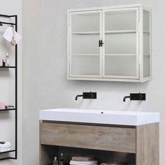 a white sink sitting under a bathroom mirror next to a shelf with towels on it