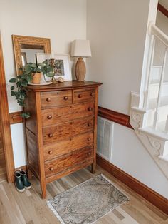 a wooden dresser sitting on top of a hard wood floor next to a stair case