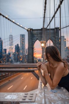 a beautiful young woman sitting on top of a bridge