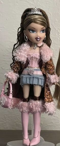 the doll is wearing a pink outfit and holding a handbag in her right hand