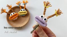 two crocheted birds are on a wooden tray and one is holding a key