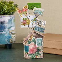 a house shaped key holder with lots of magnets on it and flowers in the background