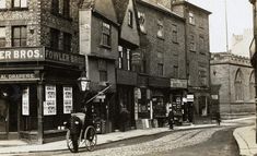 an old black and white photo of a man on a bicycle in front of a store